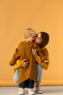 front-view-mother-kissing-kid-cheek